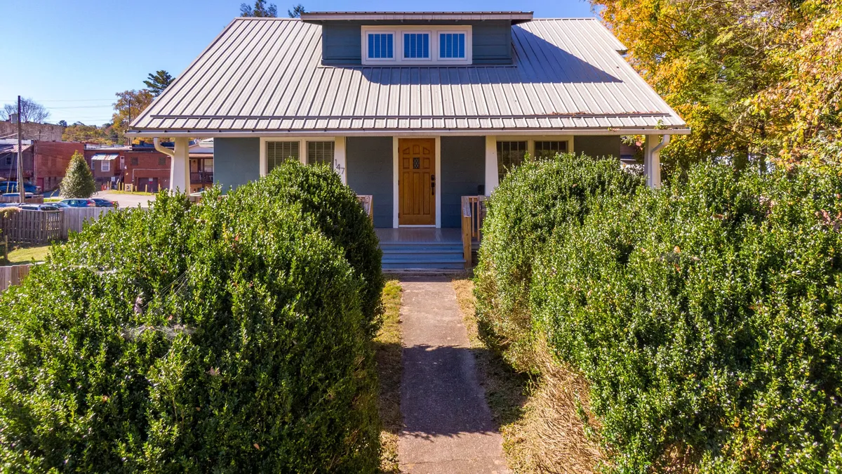 The image captures the front door of Stella Maris framed by lush bushes and a welcoming roofline. The inviting entryway hints at the proximity to the vibrant downtown, while the surrounding greenery suggests a peaceful retreat just steps from the action.