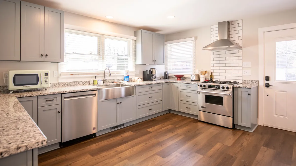 This image showcases a modern kitchen with stainless steel appliances, granite countertops, a large sink, and a kitchen island. The space is open, bright, and clearly designed for both cooking and gathering, with inviting surfaces and ample room for meal preparation or socializing.