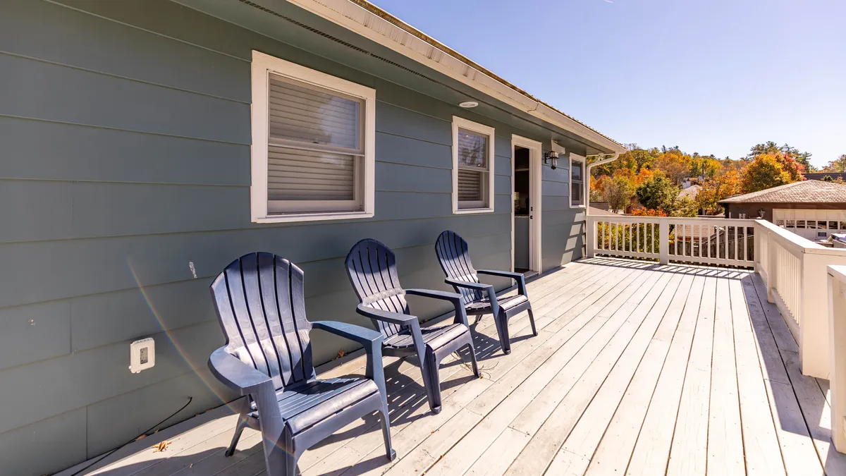 The image features blue Adirondack chairs on a wooden deck set against the home's exterior walls. The arrangement invites guests to relax outdoors, whether for sunset views, stargazing, or catching up with friends in a casual, welcoming atmosphere.