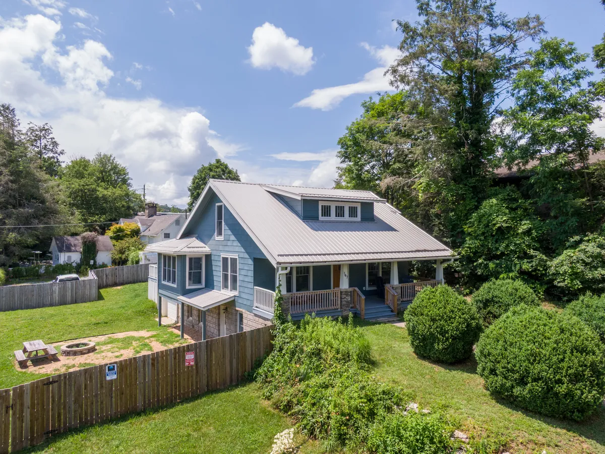 This exterior shot captures the inviting facade of Stella Maris, showcasing a spacious green lawn, a fire pit area, and, importantly, a fully fenced yard. The house is framed by greenery, creating a sense of security and openness — perfect for off-leash play and pet-friendly enjoyment.